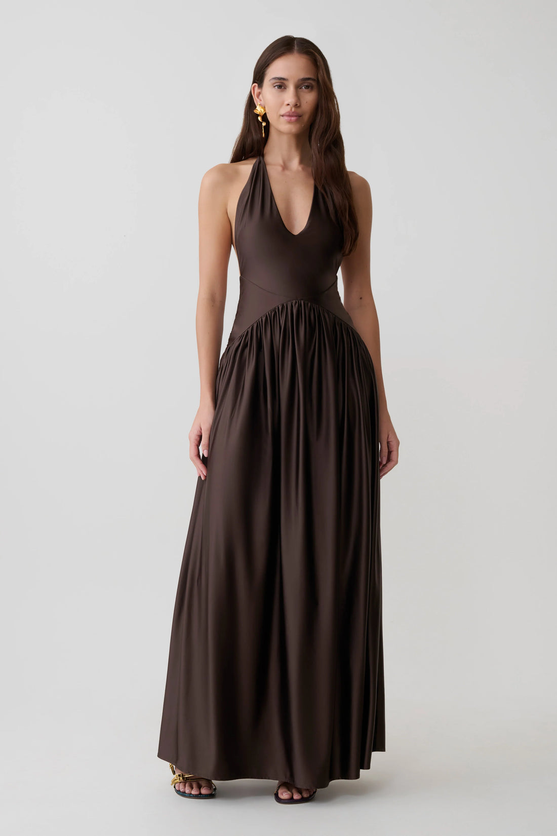 Woman wearing brown halter maxi dress with pleated skirt and gold heeled sandals — Meshki | Endless UAE