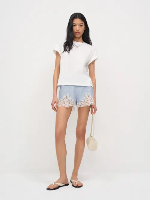 Woman wearing white t-shirt and light blue linen shorts with lace trim — Reformation | Endless UAE
