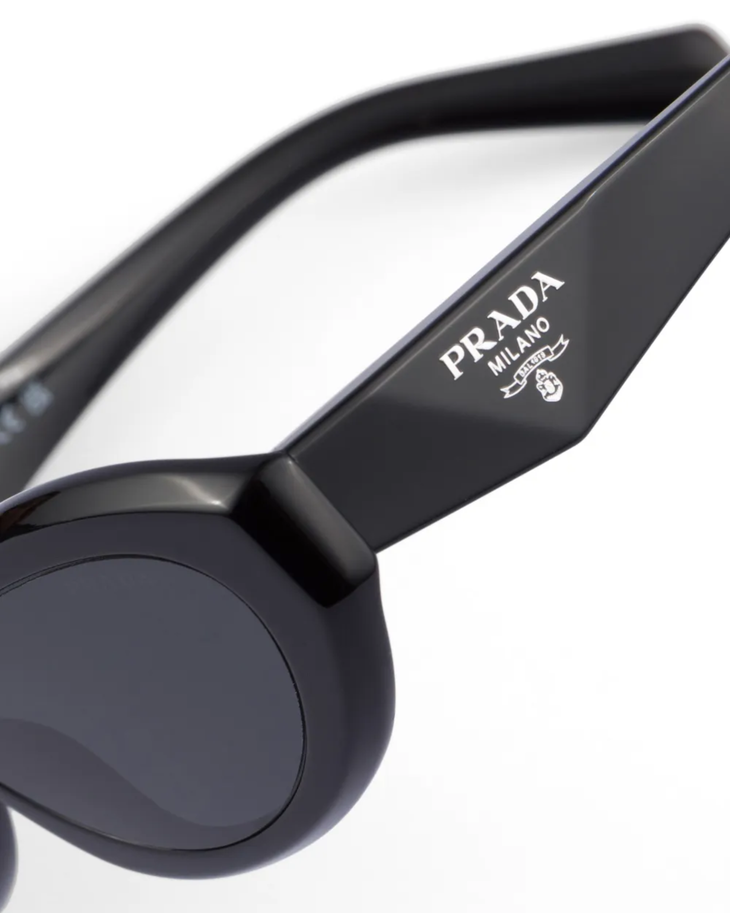Black oval-frame sunglasses with dark lenses and curved arms — Prada | Endless UAE