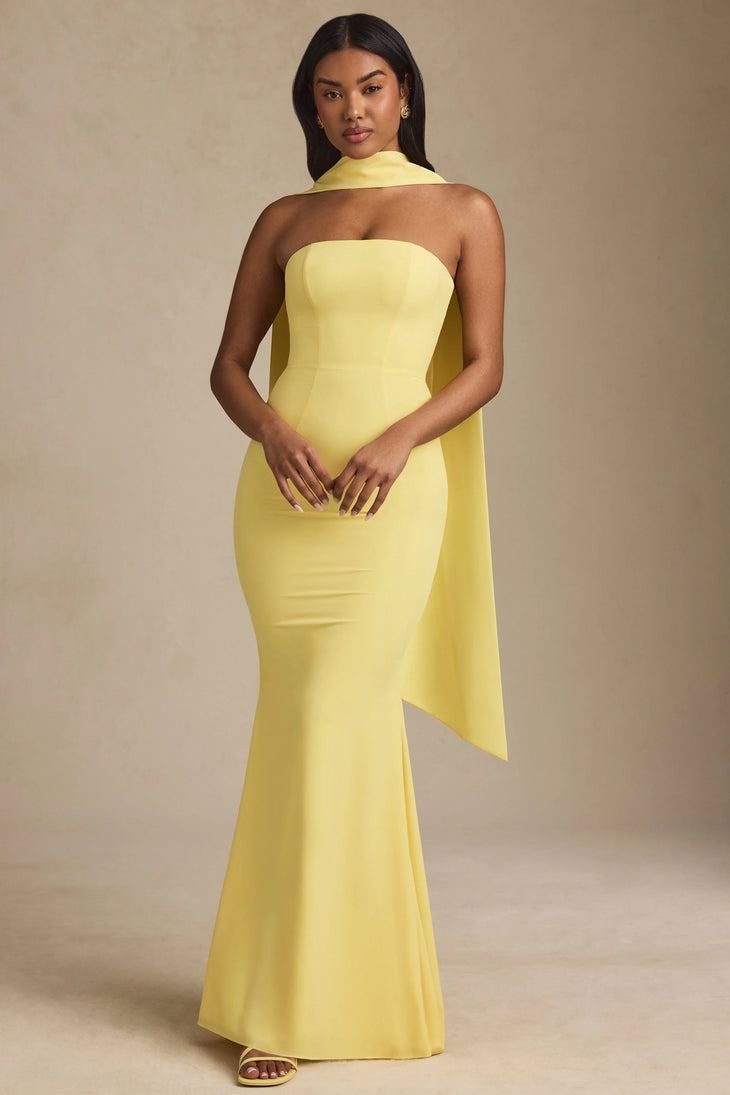 Woman wearing yellow strapless gown with draped scarf detail standing at entrance — Oh Polly | Endless UAE