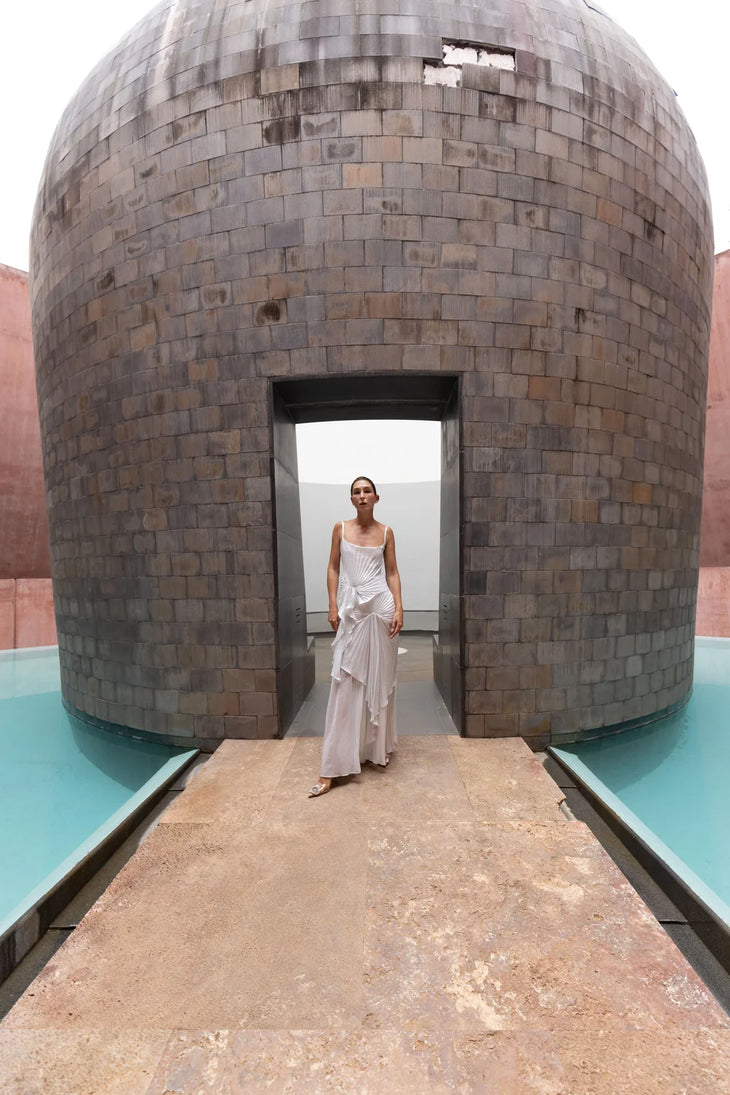 Woman wearing white draped Torrent Dress in modern architectural setting — Georgia Hardinge | Endless UAE