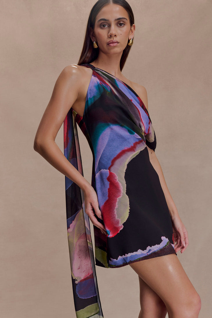 Woman wearing Daisie Chiffon Mini Dress in black with colorful abstract print drape — Meshki | Endless UAE