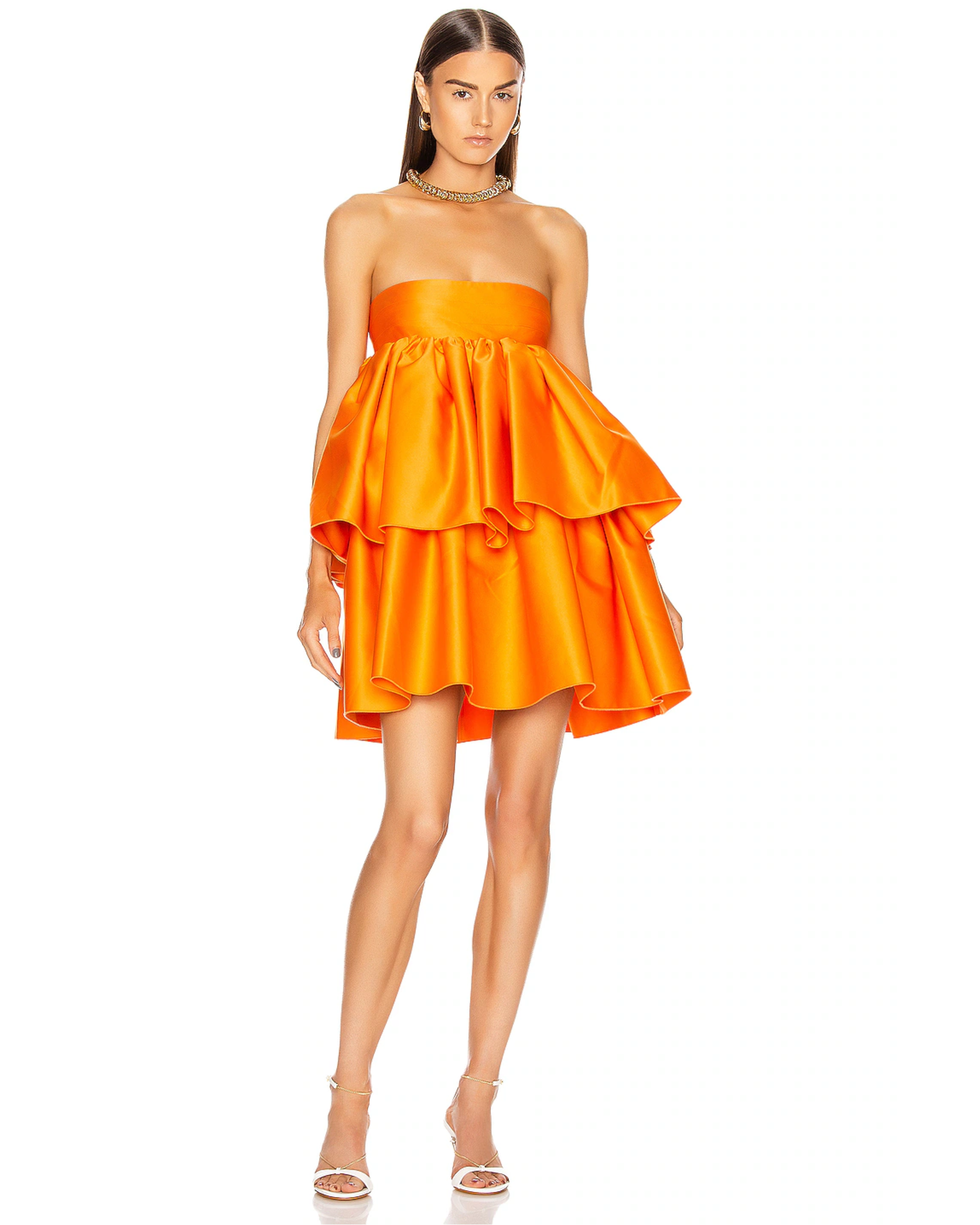 Woman wearing a strapless orange satin dress with tiered ruffled skirt and white sandals — Rotate | Endless UAE
