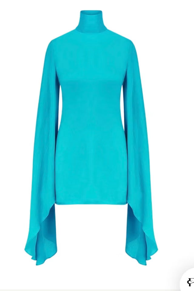 Woman wearing turquoise Farrah Dress with flowing cape sleeves at beach — Rat & Boa | Endless UAE