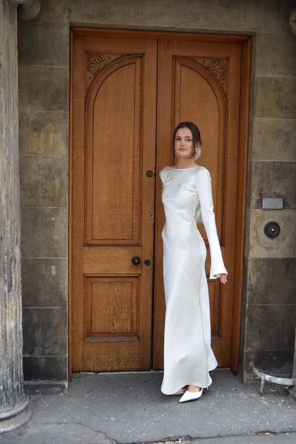 Bride in white satin Eden Dress holding white flowers — One Addington | Endless UAE