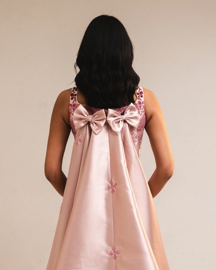 Woman wearing pink embroidered square-neck dress holding thread spools — Reema Dahbour | Endless UAE