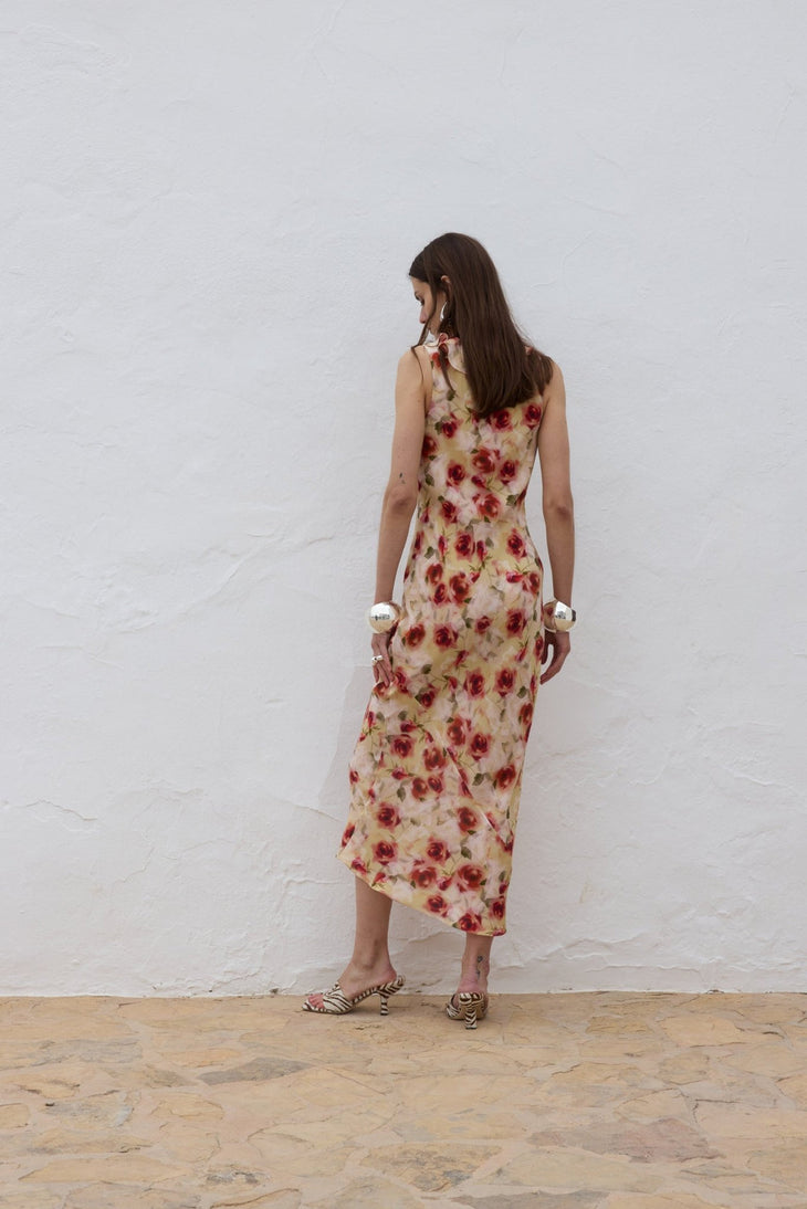 Woman wearing red floral midi dress against white wall — De La Vali | Endless UAE