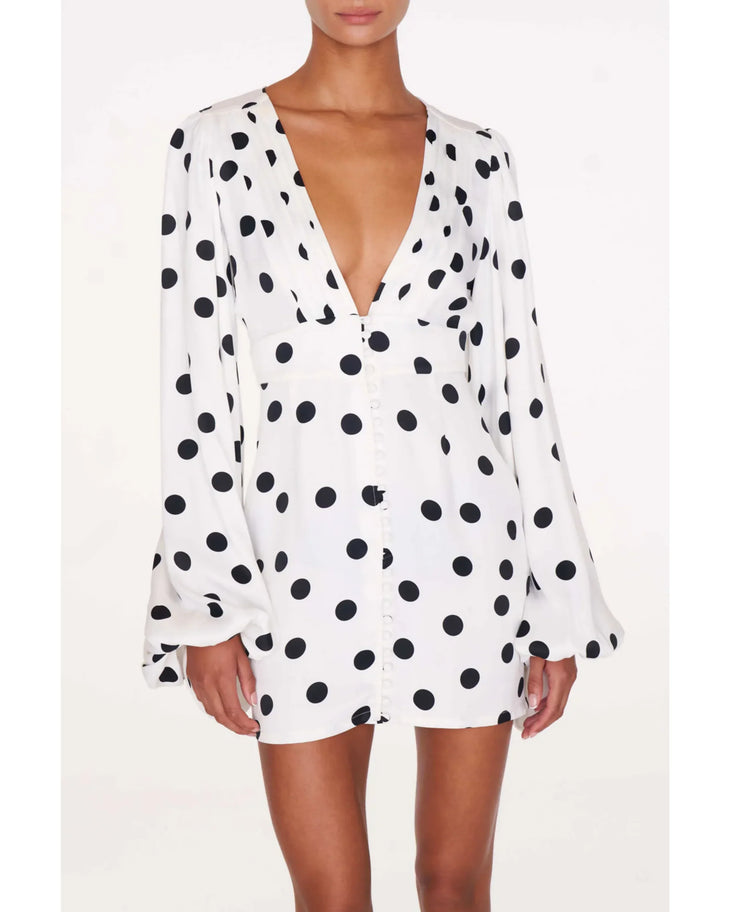 Perla Dress in white with black polka dots worn by a woman against a weathered brick wall — Rat & Boa | Endless UAE
