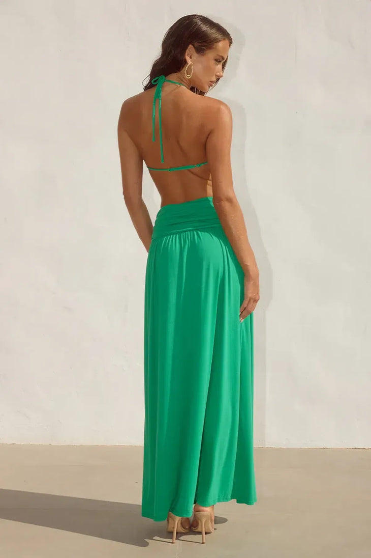 Woman wearing green halter maxi dress with cross-front cutout detail and pleated skirt — Runaway the Label | Endless UAE