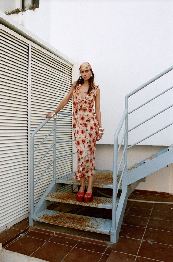 Woman wearing red floral midi dress against white wall — De La Vali | Endless UAE