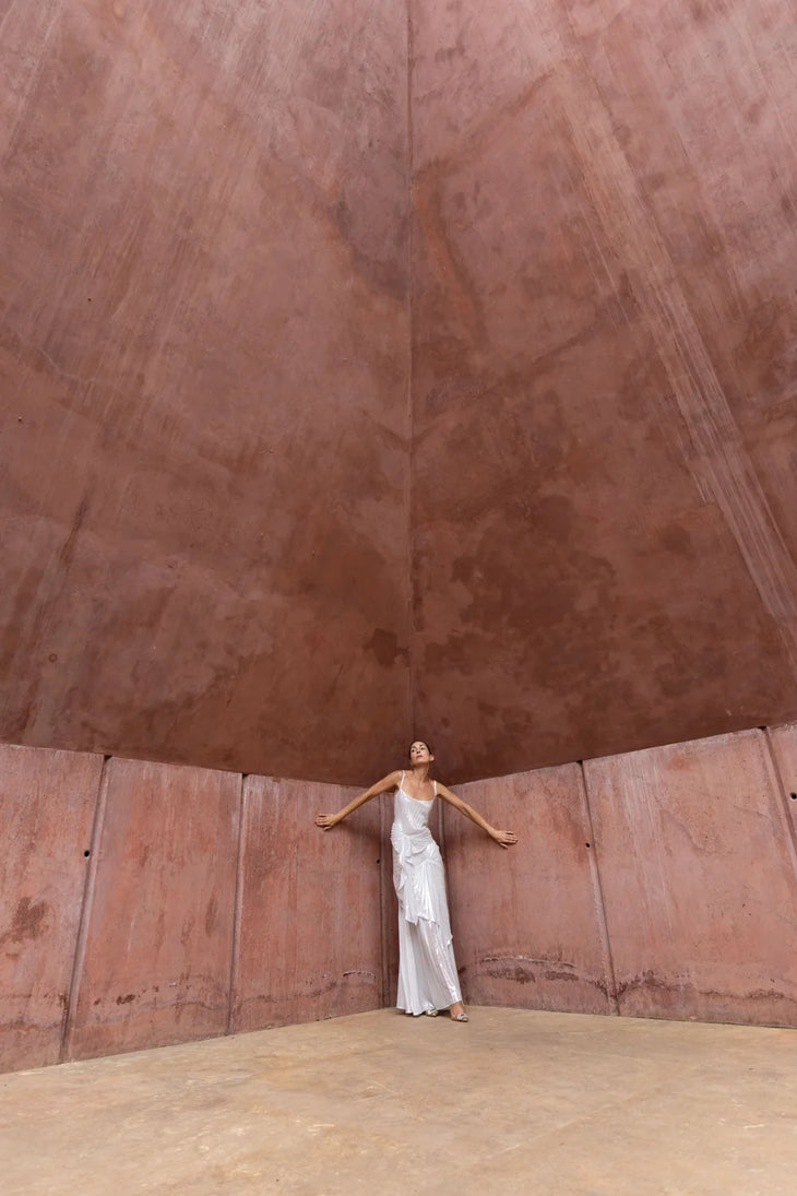 Woman wearing white draped Torrent Dress in modern architectural setting — Georgia Hardinge | Endless UAE