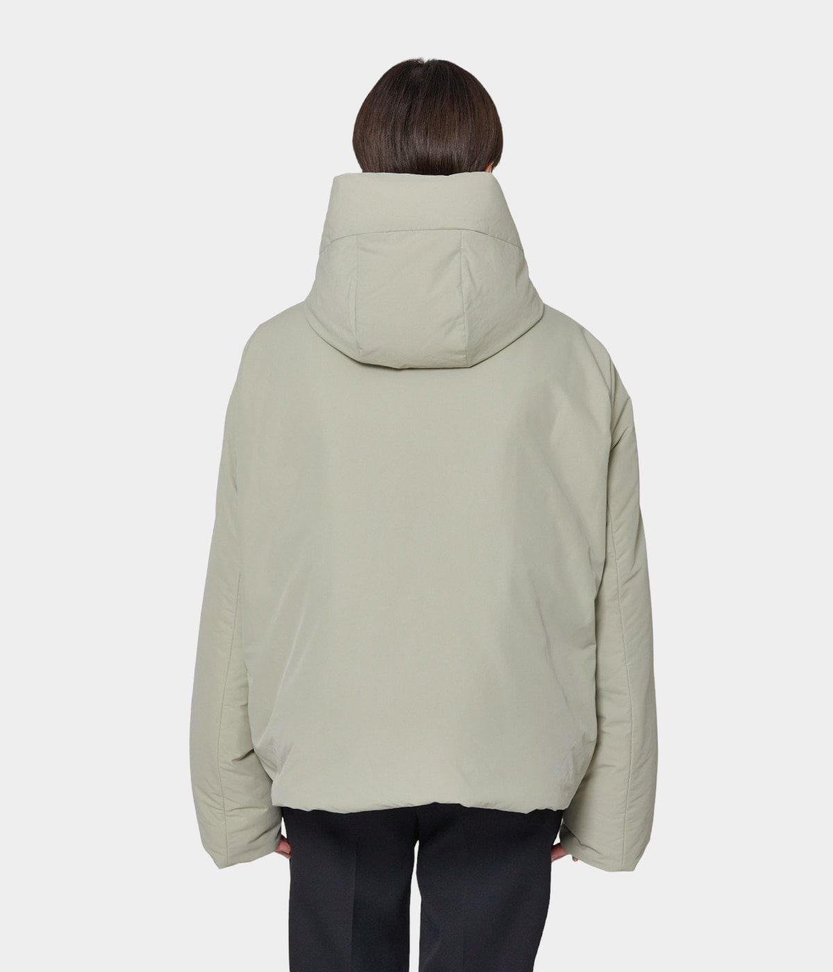 Beige puffer jacket with hood worn over dark trousers, back view — Jil Sander | Endless UAE