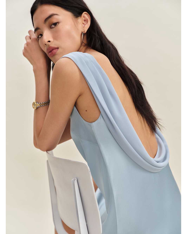Woman wearing a light blue sleeveless silk dress with draped neckline — Reformation | Endless UAE