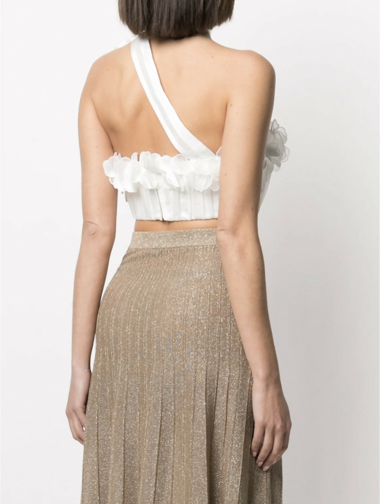 White one-shoulder crop top with ruffled floral trim and asymmetric strap detail paired with gold pleated skirt — Zimmermann | Endless UAE