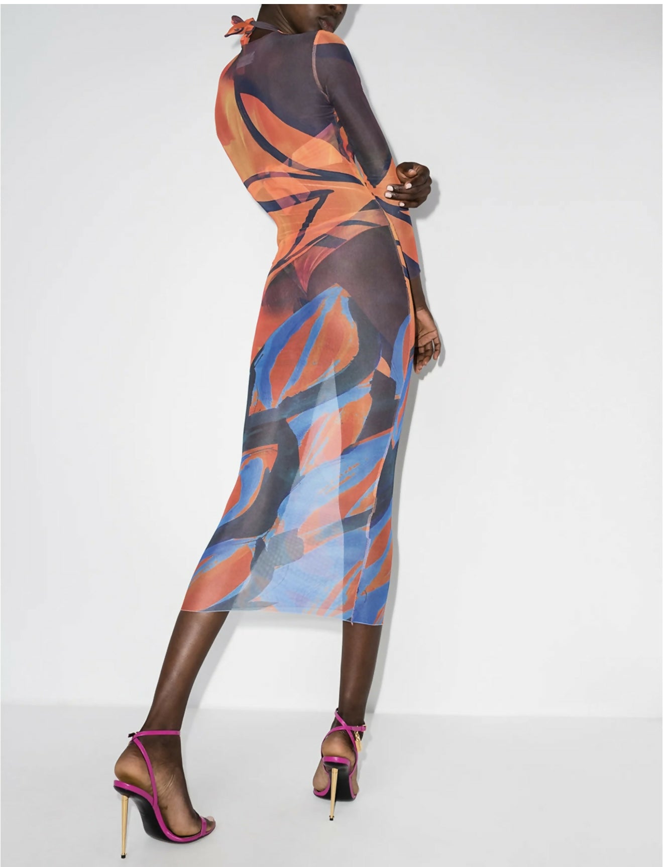 Model wearing abstract printed mesh maxi dress with long sleeves in orange, blue and purple tones, paired with pink strappy heels — Louisa Ballou | Endless UAE