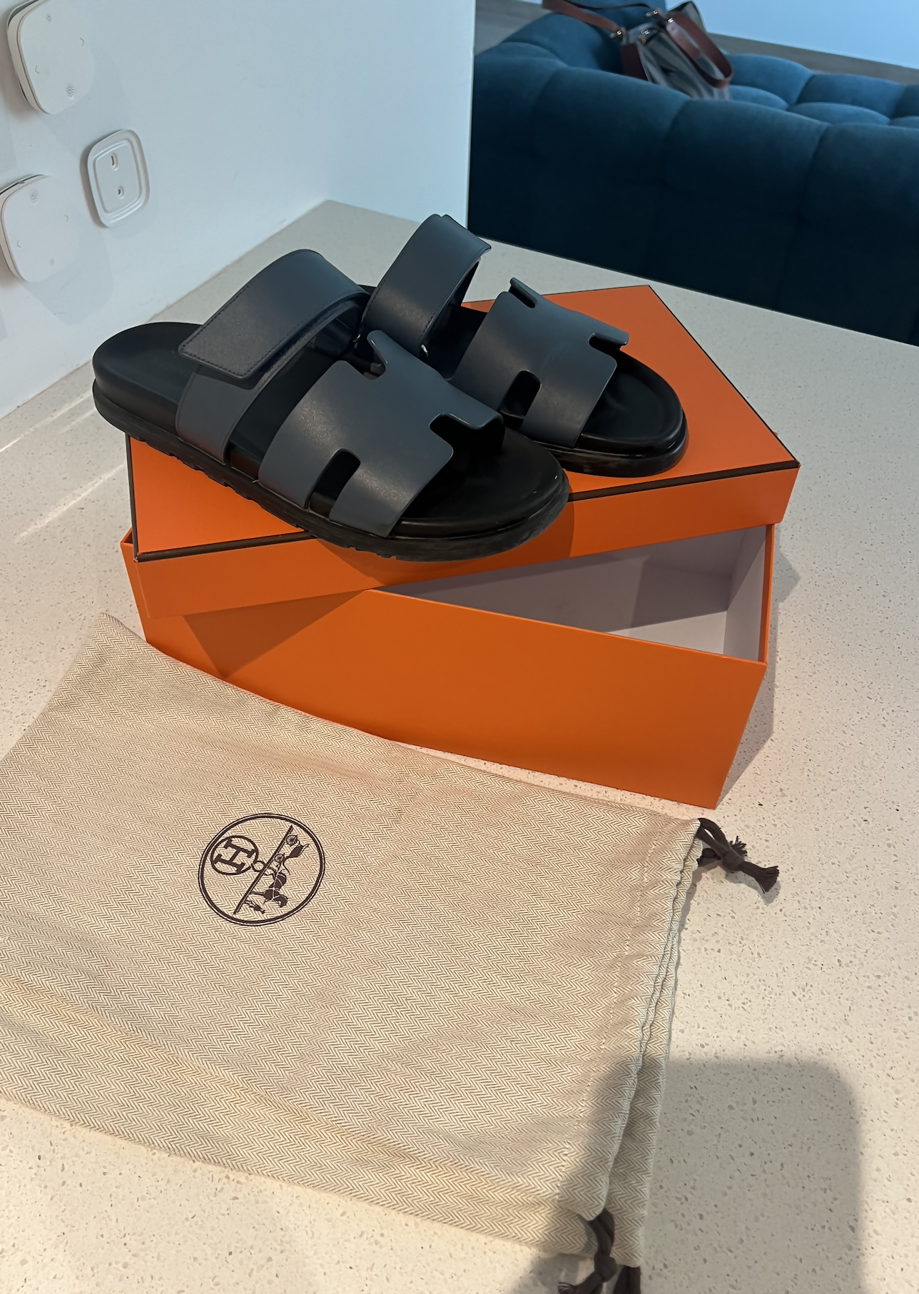 Black leather slide sandals with cutout straps displayed on orange box — Hermès | Endless UAE