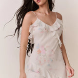 Woman modeling a cream floral ruffled maxi dress with delicate pastel details — LoveShackFancy | Endless UAE
