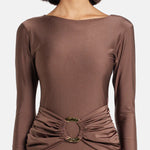 Woman wearing brown long-sleeve maxi dress with ruched waist belt and gold clutch — Lediel | Endless UAE