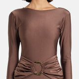 Woman wearing brown long-sleeve maxi dress with ruched waist belt and gold clutch — Lediel | Endless UAE