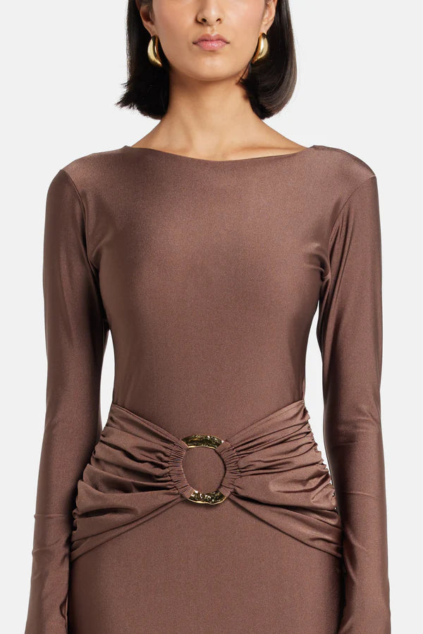 Woman wearing brown long-sleeve maxi dress with ruched waist belt and gold clutch — Lediel | Endless UAE
