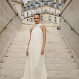 Elegant white halter neck maxi dress on model standing on Parisian staircase — Nora The Label | Endless UAE