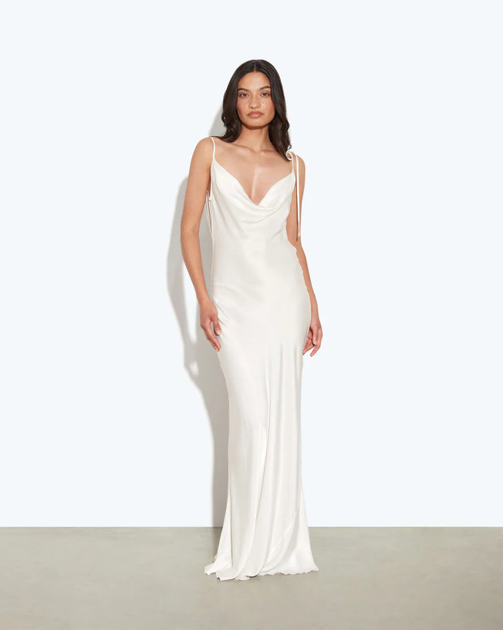 Woman wearing white cowl neck sleeveless maxi dress against textured beige wall — Rat & Boa | Endless UAE