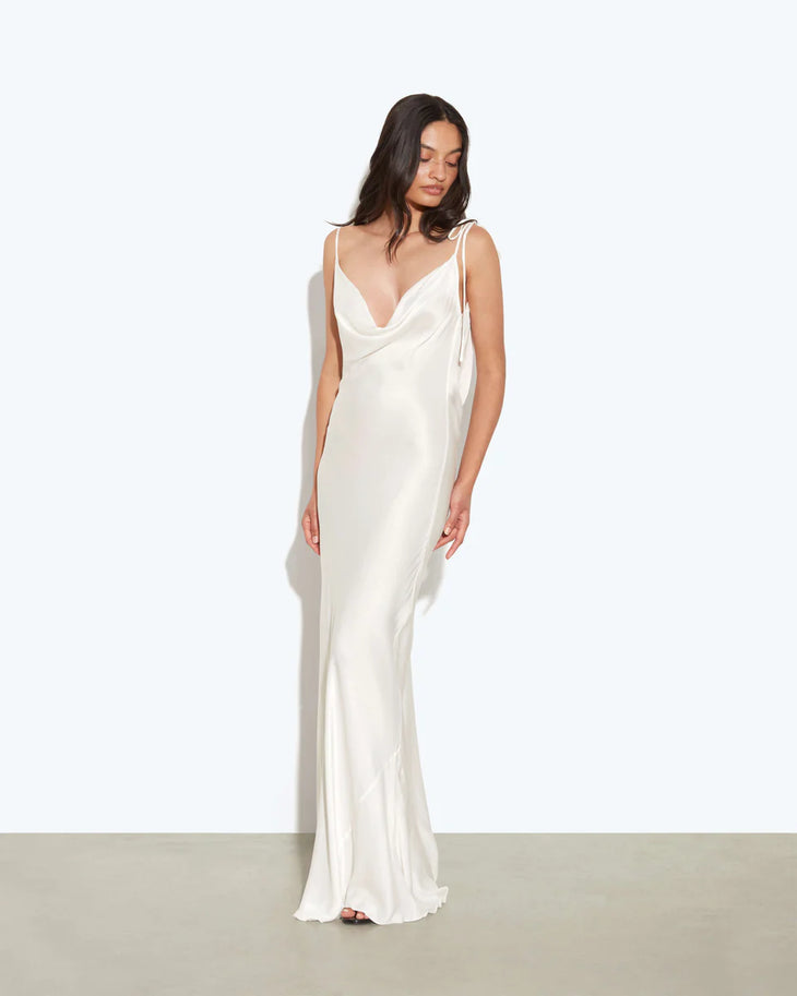 Woman wearing white cowl neck sleeveless maxi dress against textured beige wall — Rat & Boa | Endless UAE