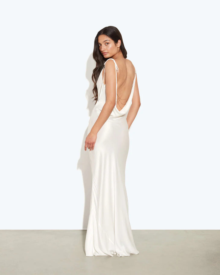 Woman wearing white cowl neck sleeveless maxi dress against textured beige wall — Rat & Boa | Endless UAE