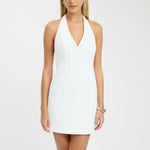 White halter neck mini dress with low back and V-neckline worn by blonde model — Kookai | Endless UAE