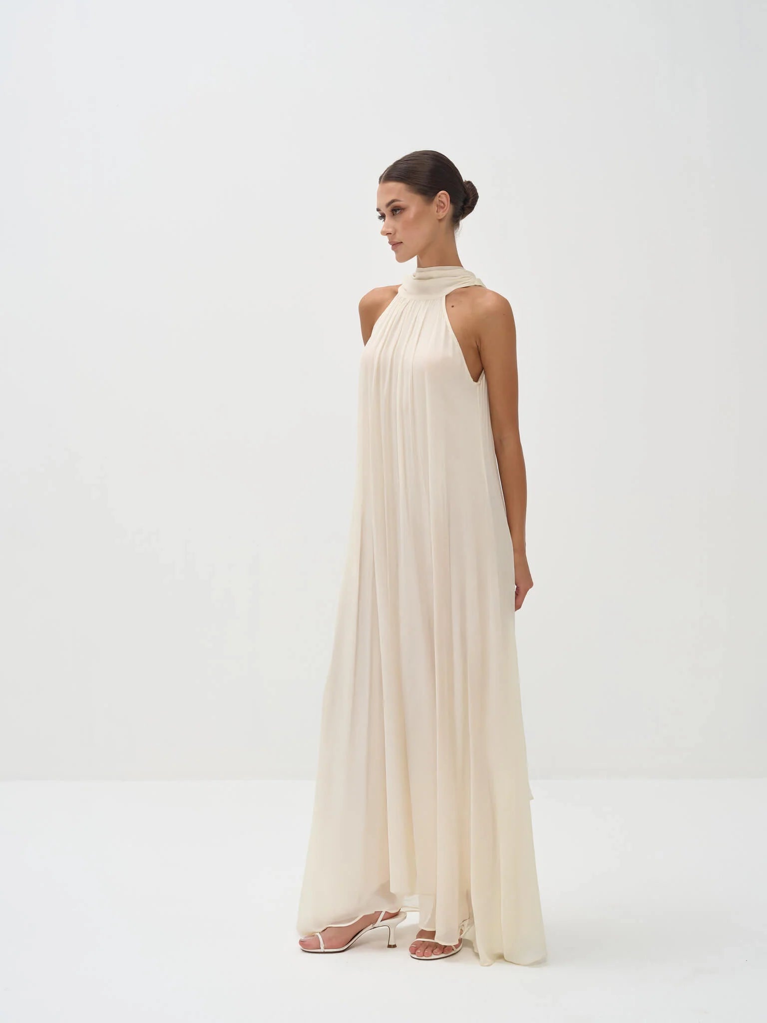 Elegant cream halter neck maxi dress with flowing pleated fabric and floor-length silhouette — Nora The Label | Endless UAE