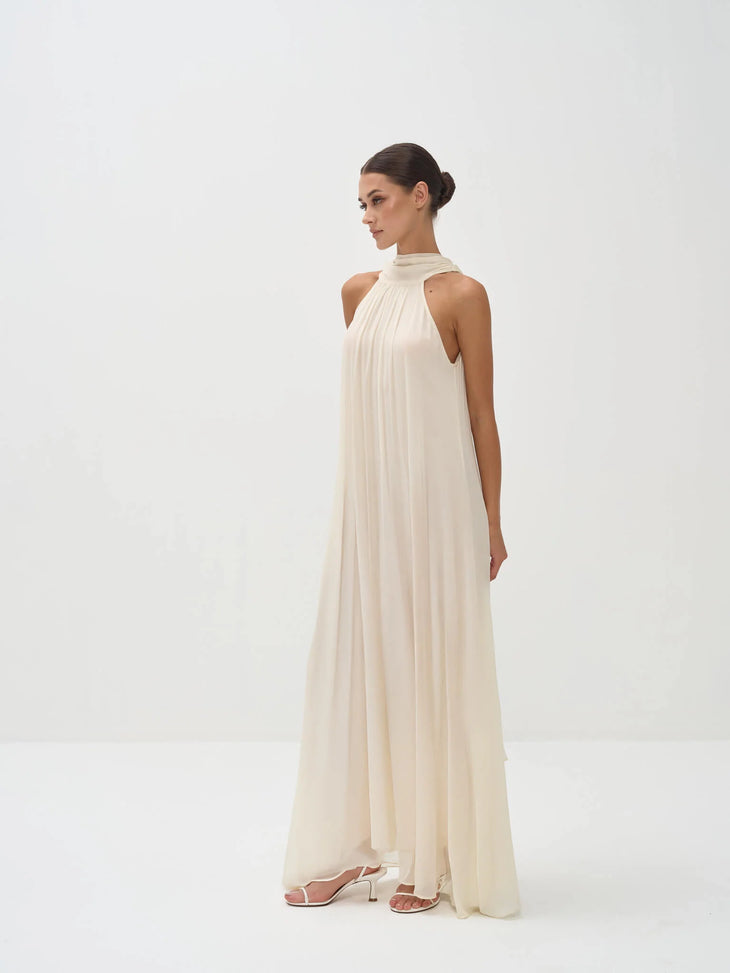 Elegant cream halter neck maxi dress with flowing pleated fabric and floor-length silhouette — Nora The Label | Endless UAE