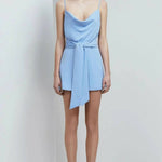Cornflower blue cowl neck mini playsuit with tie waist detail and thin straps on model with strappy heels — Keepsake The Label | Endless UAE