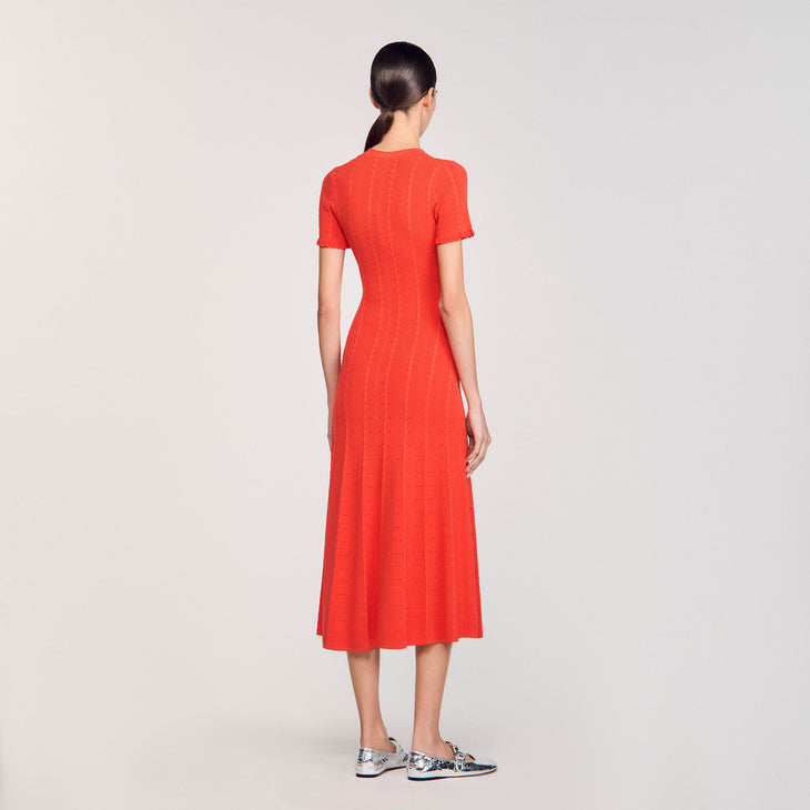 Woman wearing vibrant coral red knit maxi dress with short sleeves and textured vertical ribbing, viewed from behind — Sandro | Endless UAE