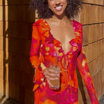 Woman wearing vibrant orange and pink floral print mini dress with long sleeves and ruffle details — Rat & Boa | Endless UAE