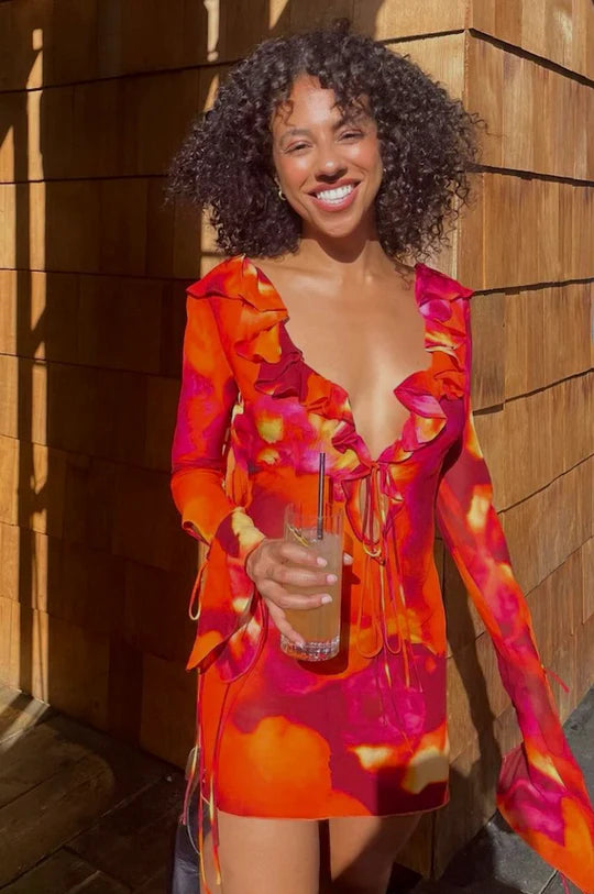 Woman wearing vibrant orange and pink floral print mini dress with long sleeves and ruffle details — Rat & Boa | Endless UAE