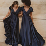 Two women in navy blue floor-length bridesmaid dresses with flutter sleeves and V-necklines — You&I Bridal | Endless UAE