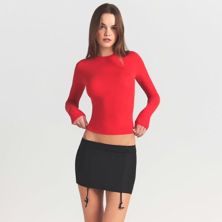 Red long sleeve fitted t-shirt paired with black mini skirt — Skims | Endless UAE
