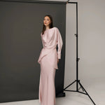 Woman wearing pale pink satin co-ord set with draped top and maxi skirt in studio setting — Nora The Label | Endless UAE