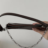 Dark brown croc-embossed mini shoulder bag with chain detail held in hand — By Far | Endless UAE