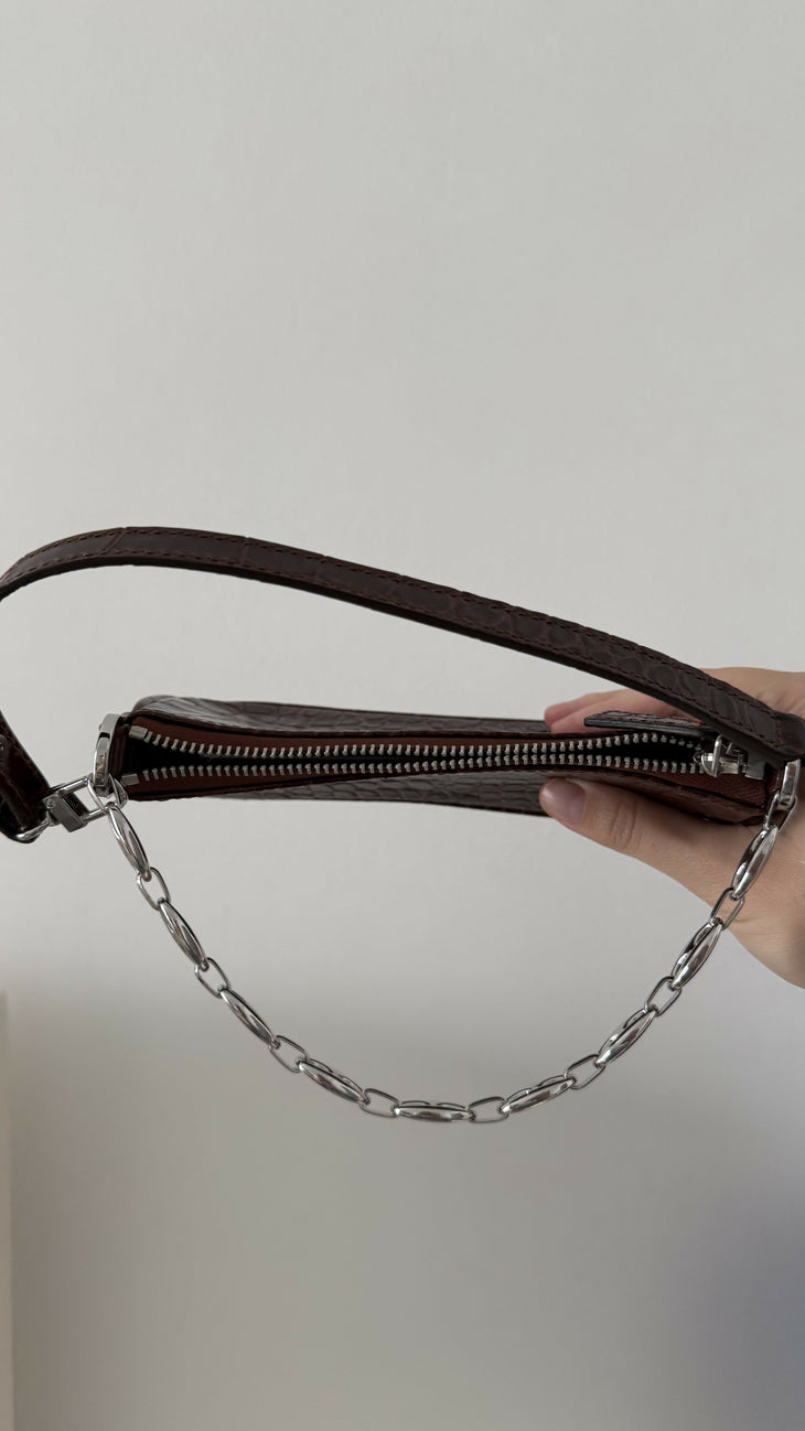 Dark brown croc-embossed mini shoulder bag with chain detail held in hand — By Far | Endless UAE