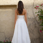 Woman in white strapless midi dress with full skirt and heels against textured wall — Cleopatress | Endless UAE