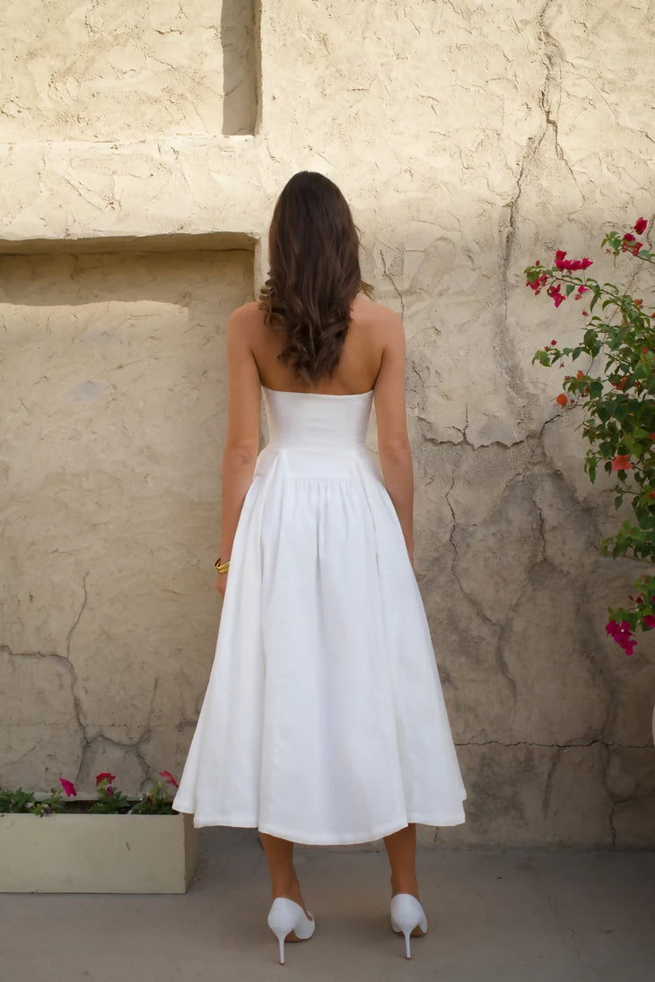 Woman in white strapless midi dress with full skirt and heels against textured wall — Cleopatress | Endless UAE