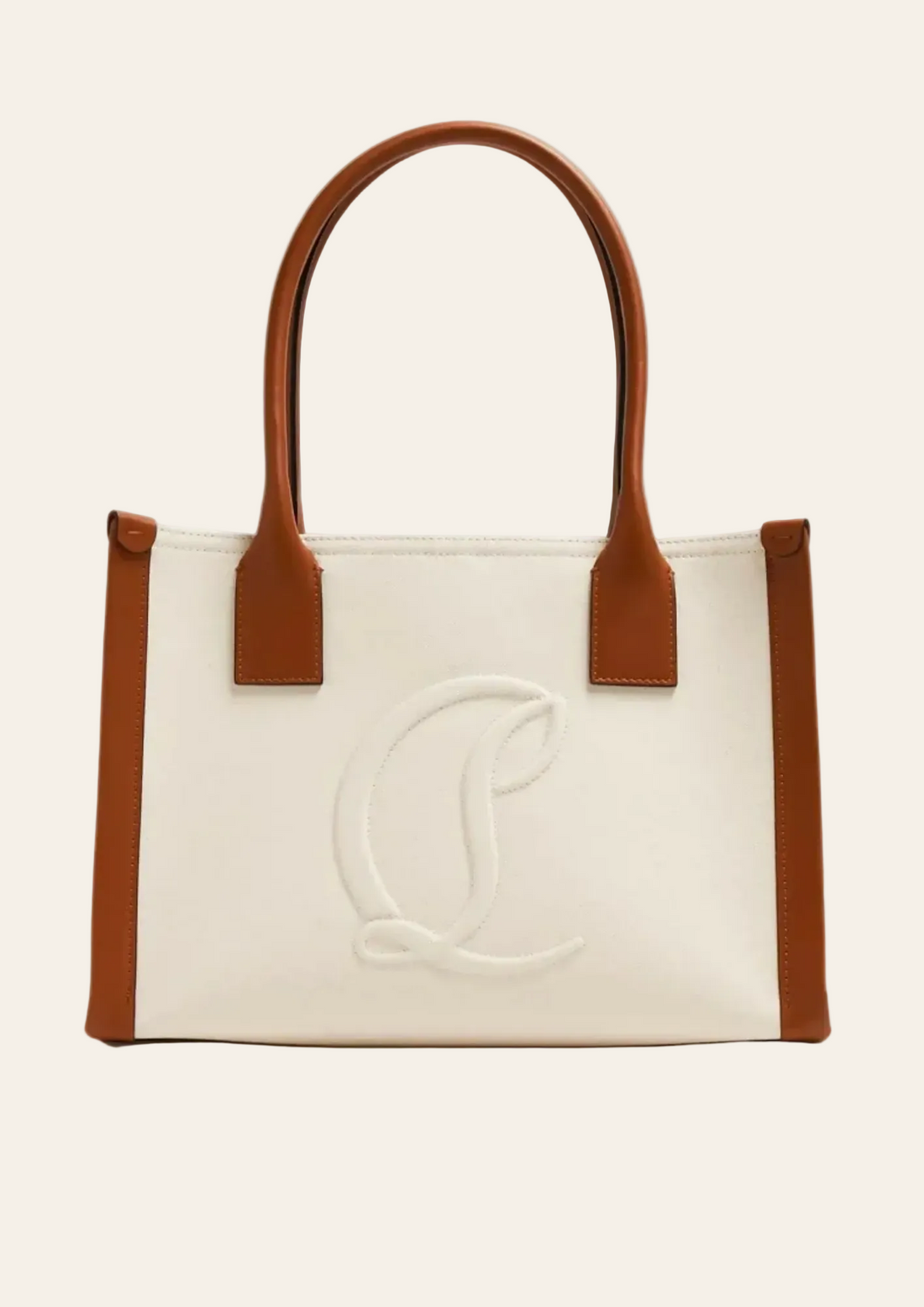 Woman holding cream canvas tote bag with brown leather handles and trim, wearing tan suede jacket and white skirt — Christian Louboutin | Endless UAE