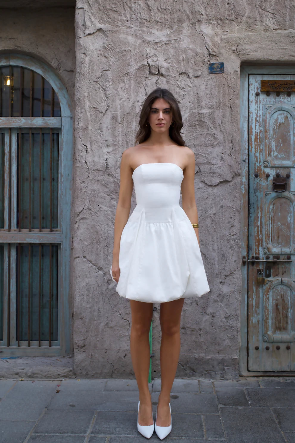 White strapless mini dress with bubble skirt hem and fitted bodice worn with white heels — Cleopatress | Endless UAE
