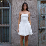 White strapless mini dress with bubble skirt hem and fitted bodice worn with white heels — Cleopatress | Endless UAE