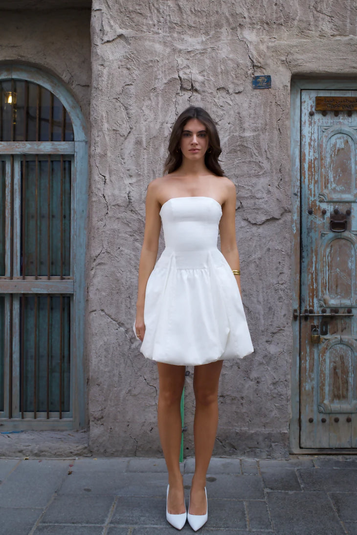 White strapless mini dress with bubble skirt hem and fitted bodice worn with white heels — Cleopatress | Endless UAE