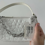 White quilted mini shoulder bag with silver hardware held up against neutral background — By Far | Endless UAE
