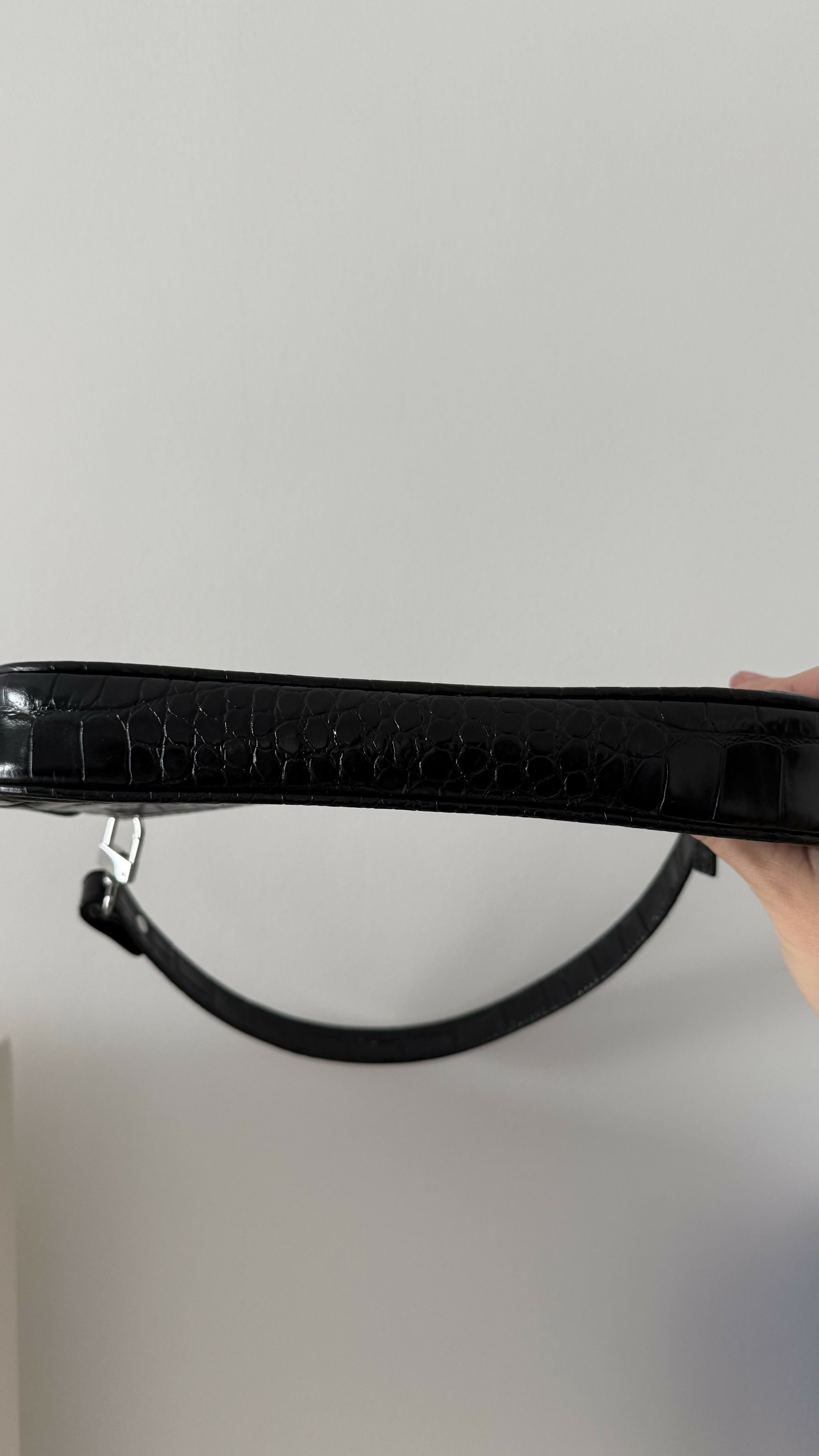 Black crocodile embossed leather shoulder bag held in hand against white background — By Far | Endless UAE