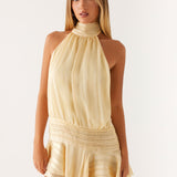 Woman wearing a pale yellow halter neck mini dress with pleated waist detail and ruffled hem — Peppermayo | Endless UAE
