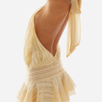 Woman wearing pale yellow chiffon mini dress with deep V-neckline, pleated waist, ruffled skirt and shoulder ties — Peppermayo | Endless UAE
